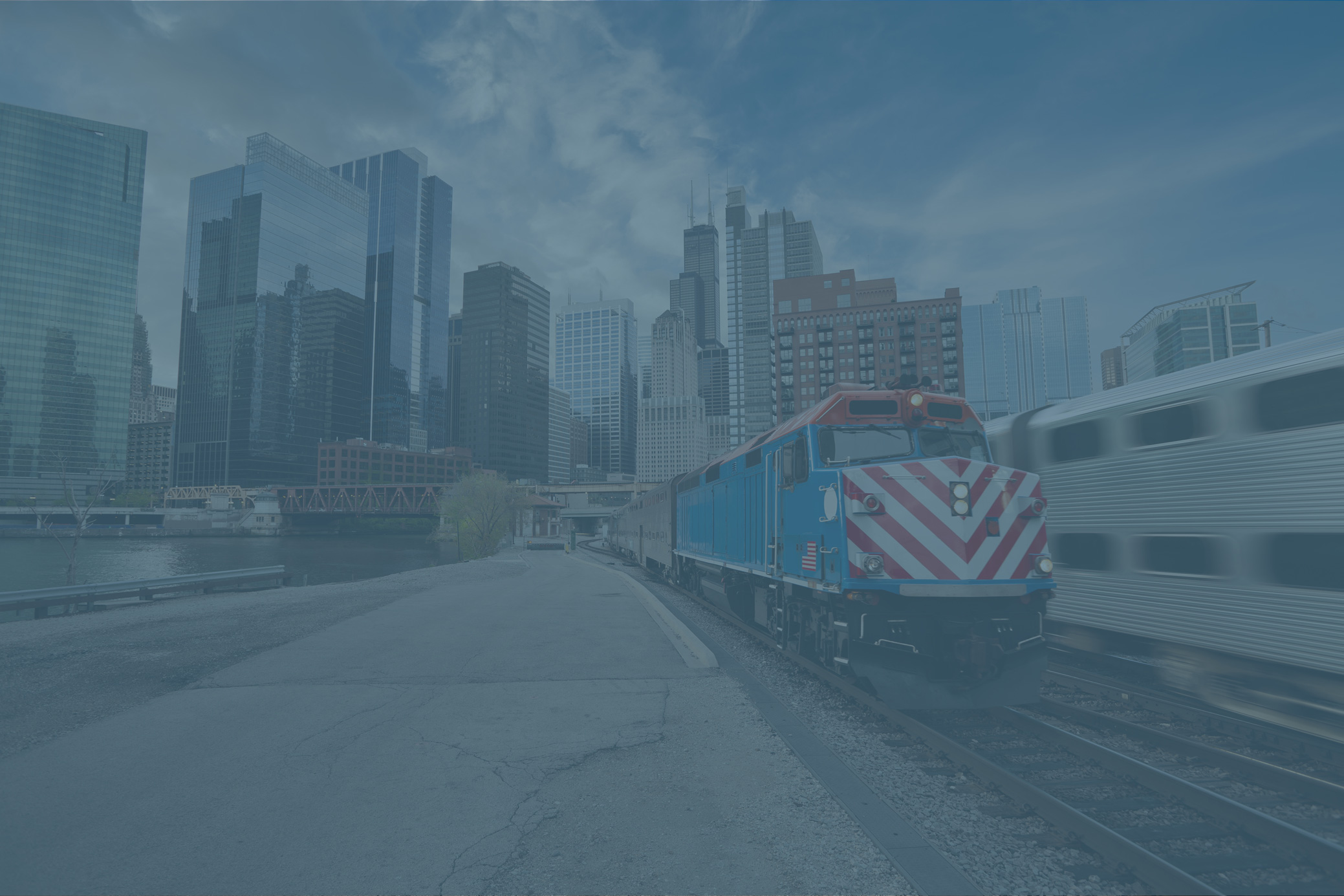 Chicago Metra train with red, white and blue locomotive, downtown district in background